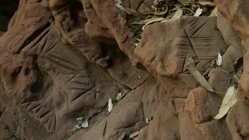 A dirty rock face covered in tally like carvings