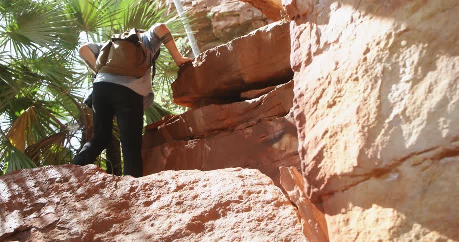 A man is climbing up the rocks on a sunny day