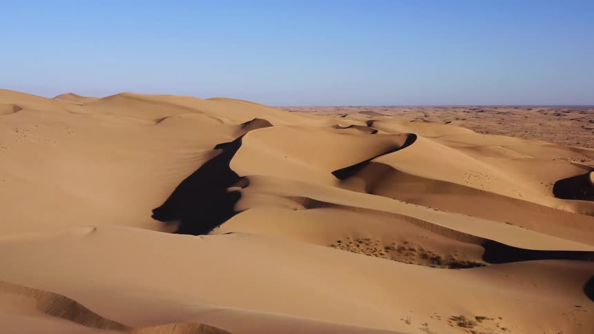 Dunes in the desert sit under the blue sky