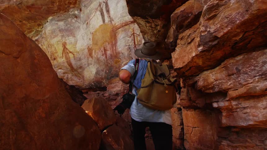 A man is walking through the wilderness with a camera