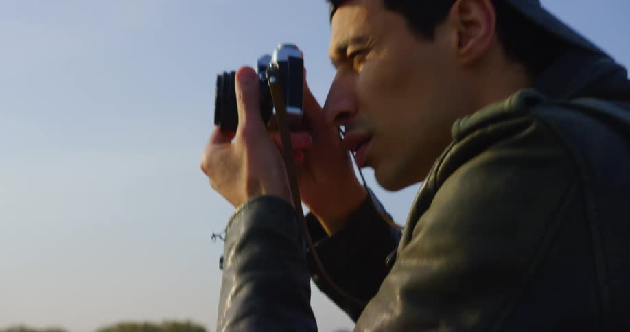 A teenager looks through his camera lens