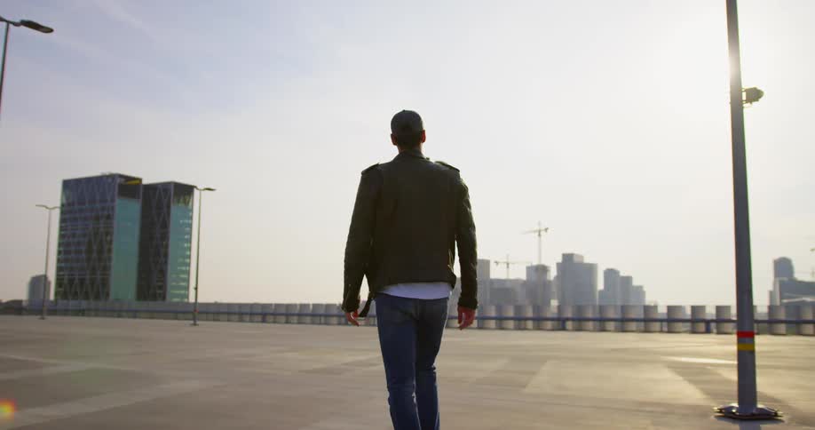 A man walks across a tall city building rooftop