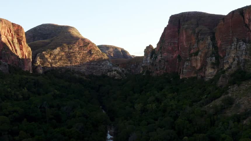 A river surrounded by trees with a cliff the sky and clouds in the background