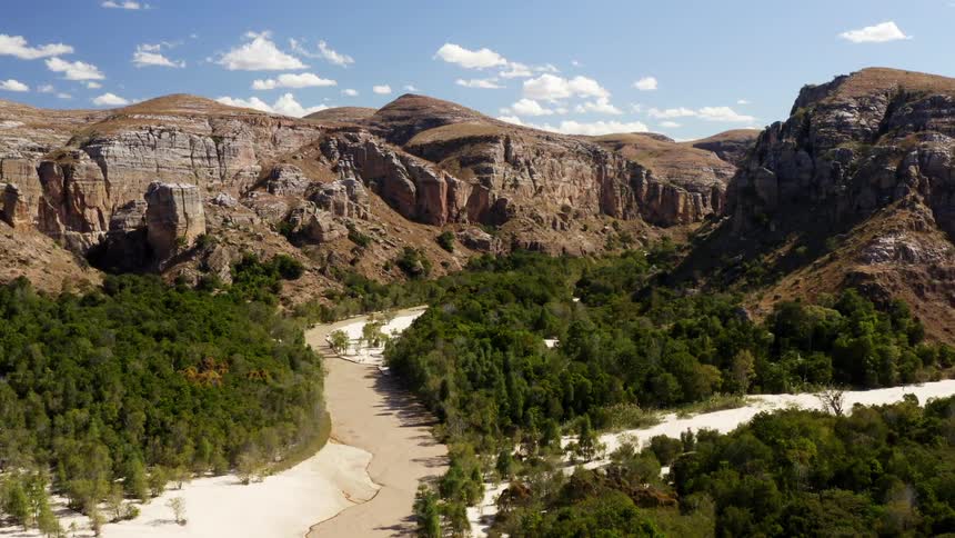 A river surrounded by trees with cliffs the sky and clouds in the background
