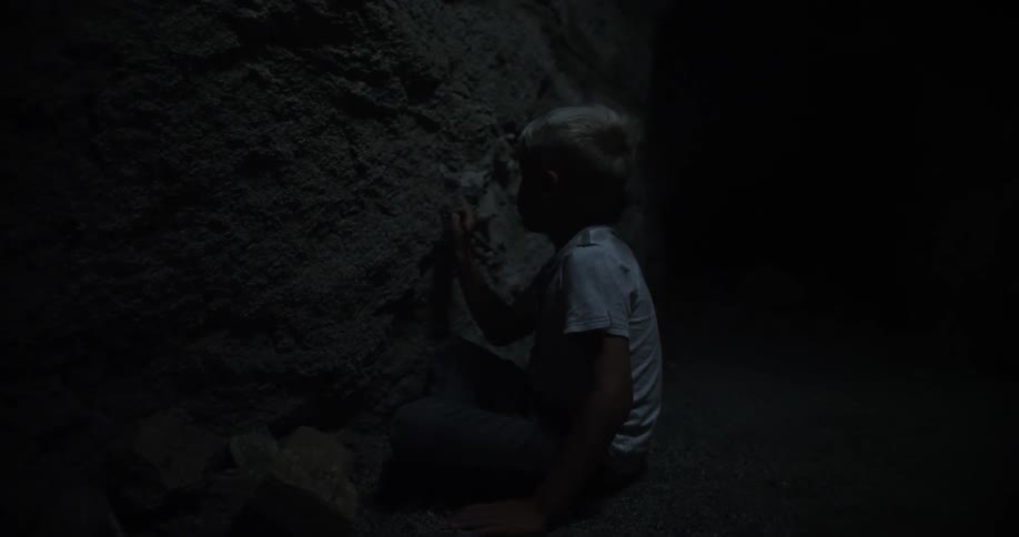 A boy scrapes a stone wall with a stick