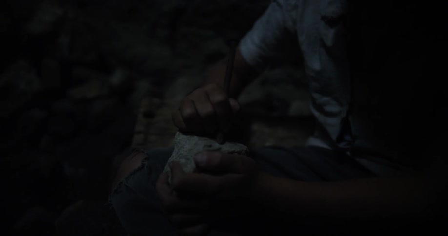 A person scratches a rock with a stick
