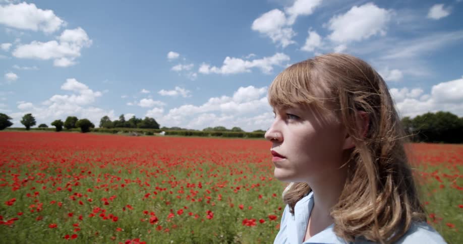 A woman is walking past the field full of flowers