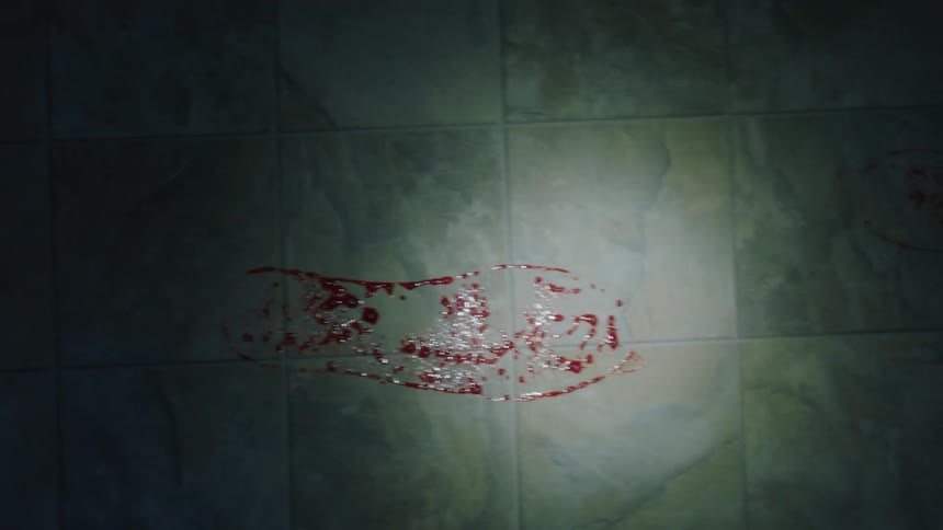 Flashlight shines on bloody shoe prints on tile in shadowy area