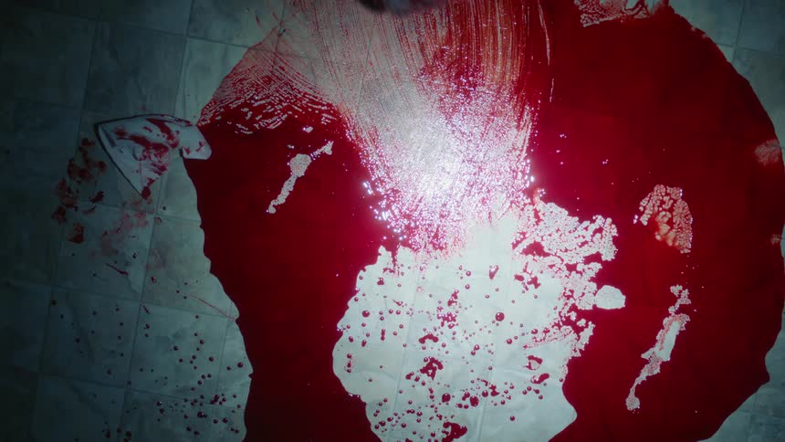 Mop pushes through crimson liquid cleaning it off tiled floor