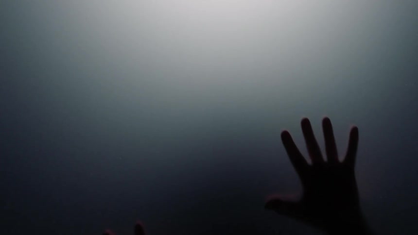 Hands on a glass with gray and lights in the background