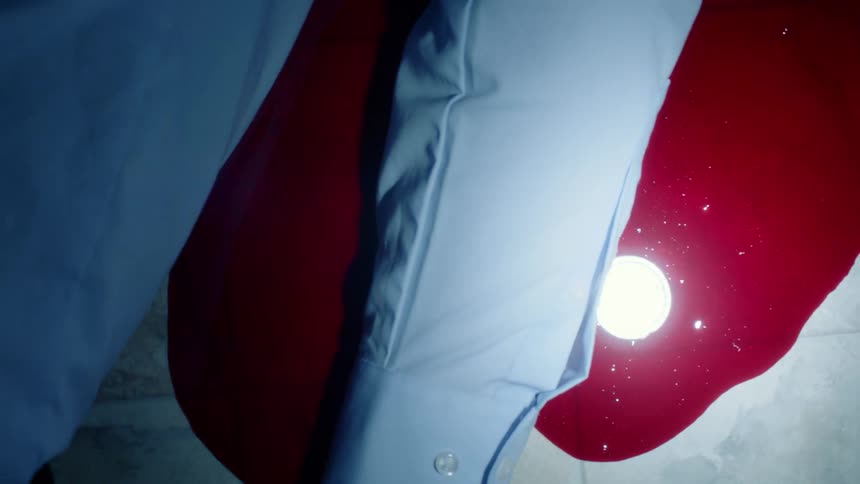 Dead body on the ground in a pool of fresh red blood in a dimly lit room