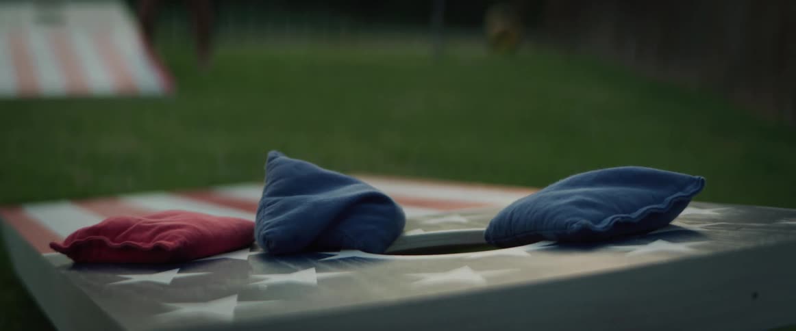 Corn hole bags are tossed onto a corn hole board painted like an american flag