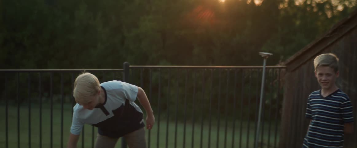 A boy tosses a bean bag and then hands one to his younger brother as they play a game in their back yard