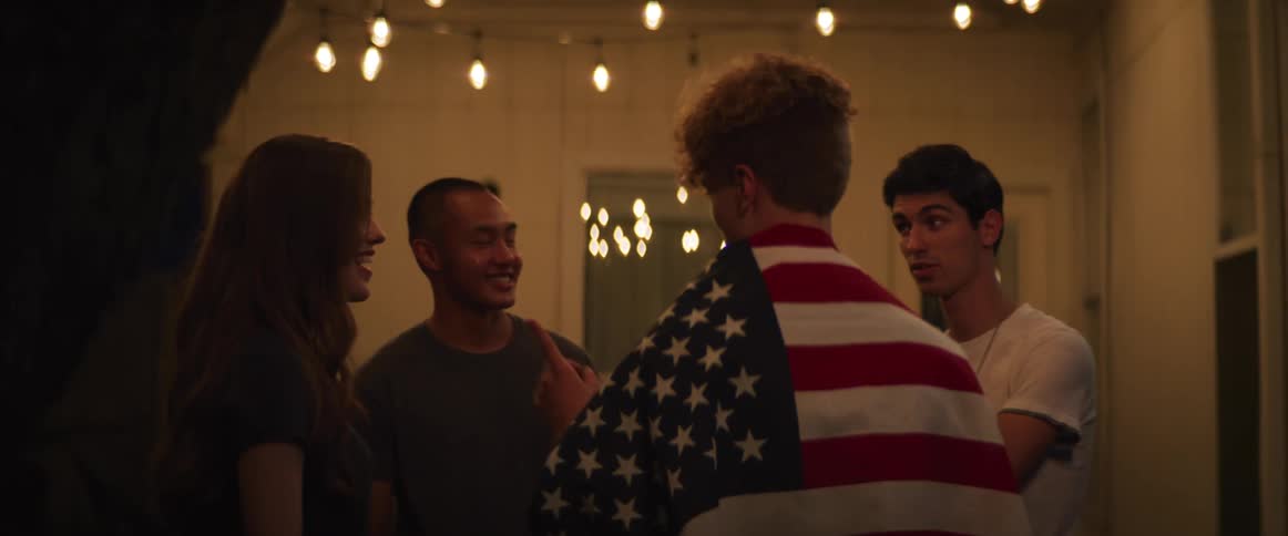 Three men and a woman standing and talking with a man draped in the american flag
