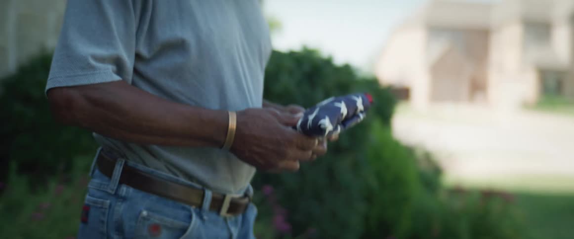 A man carries a flag into his yard