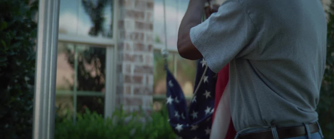A man hangs a flag outside his home