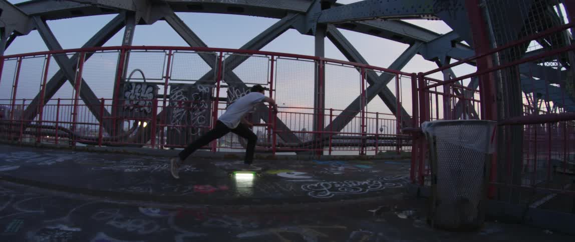 A teenager skates across a bridge