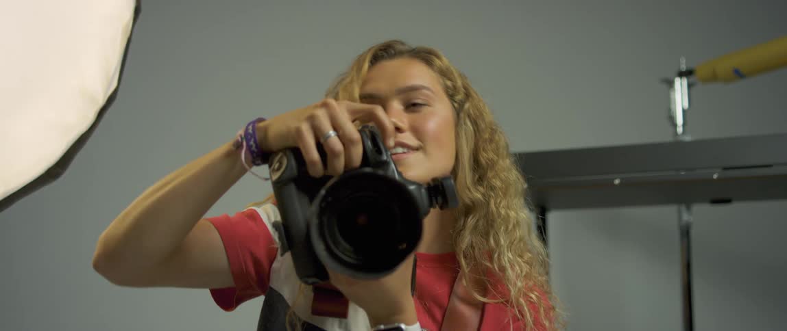 A young woman takes photos and then a young man comes and bends down next to her