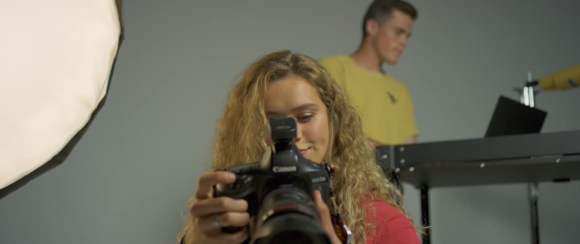 A woman holds up a professional camera to her face and takes a picture