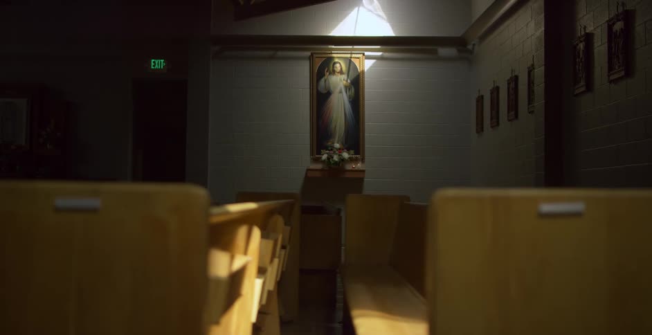 Wooden pews and a painting of christ in a church building