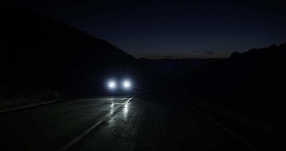 A vehicle drives on a rural road at night