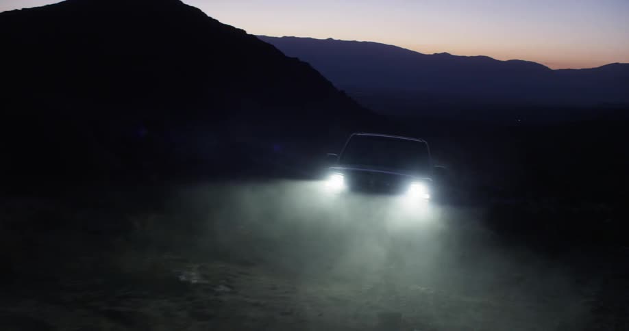 A vehicle drives in the mountains at dusk