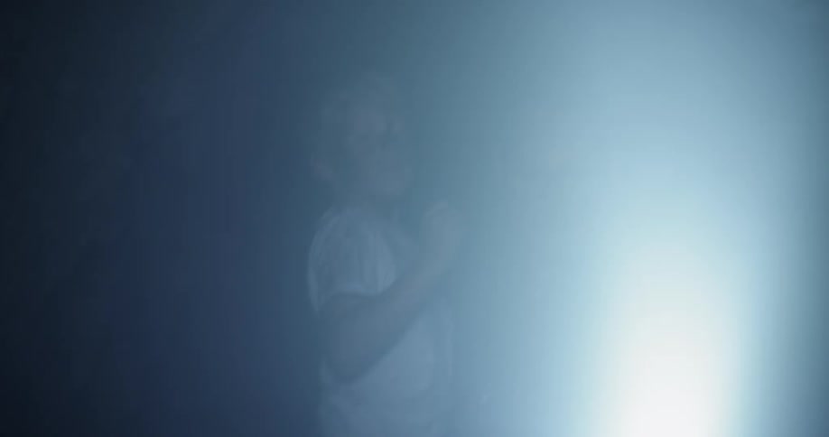 Man with a flashlight carrying a boy through a dark cave like area