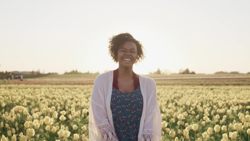 A woman is laughing in a field full of tulips