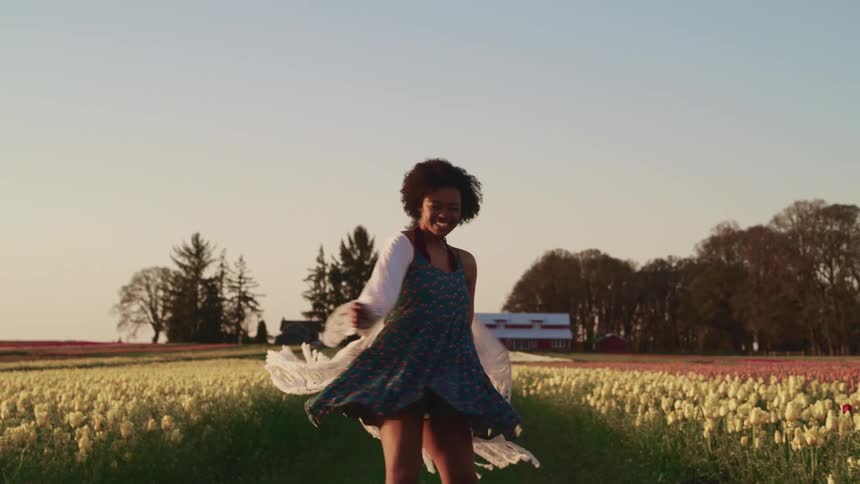 A woman running and twirling around in a field of flowers