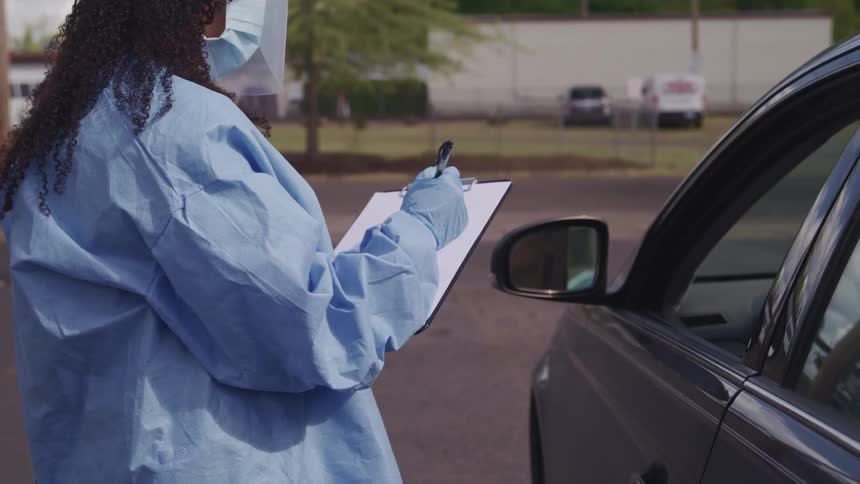 A nurse questions a person in their car