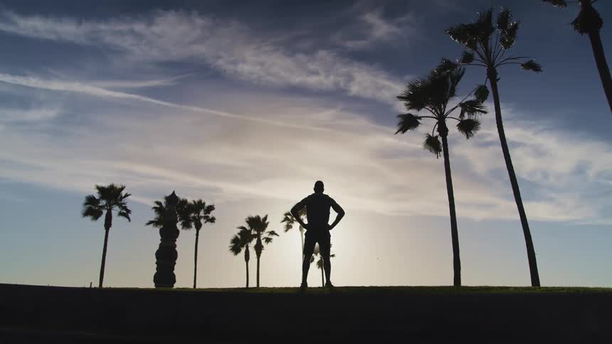 A male standing outside near palm trees