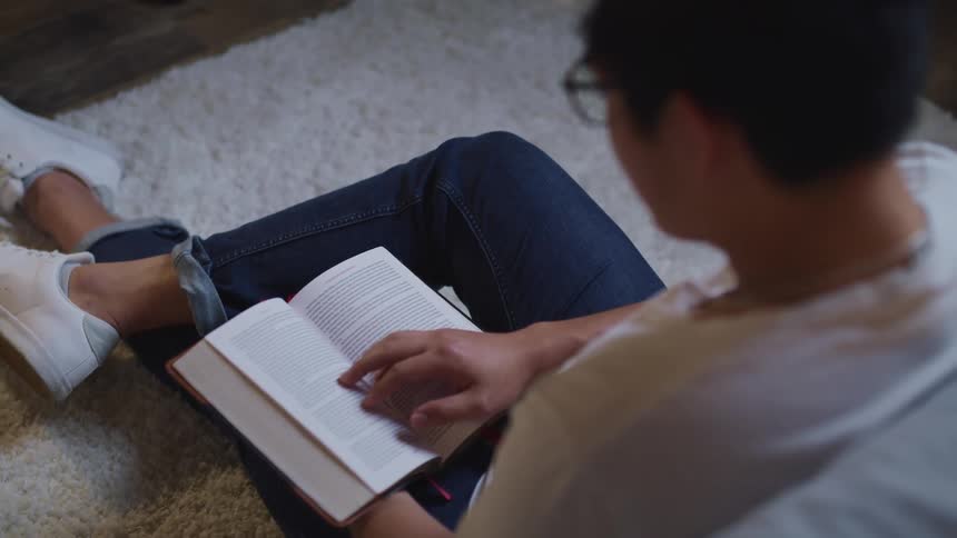 A teenage boy sits and reads at home