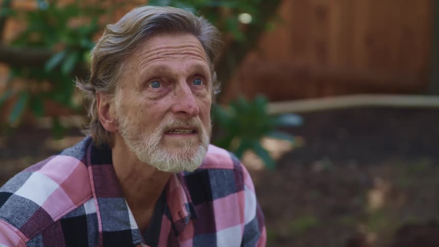 An elderly white man outside looks around
