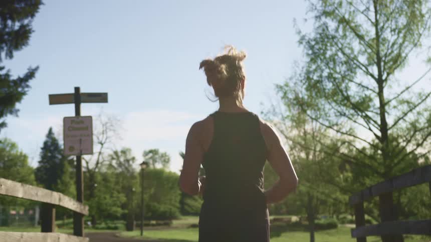 A woman jogs across a bridge on a sunny day