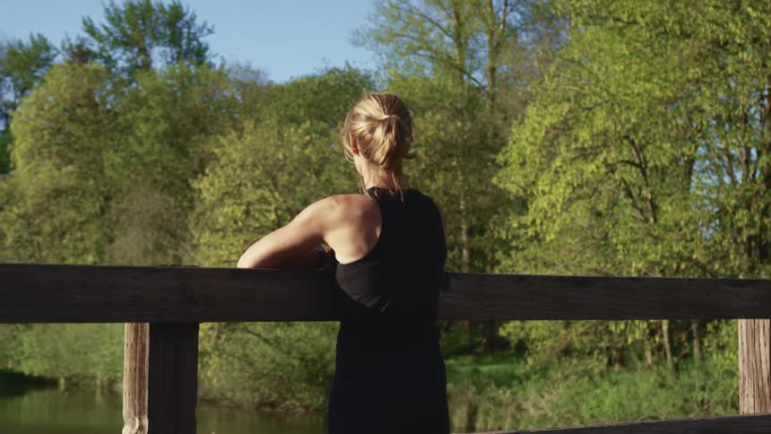 A woman is leaning against the railing on the bridge