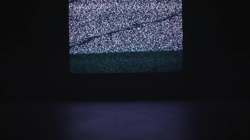 A television screen flashes static in the dark