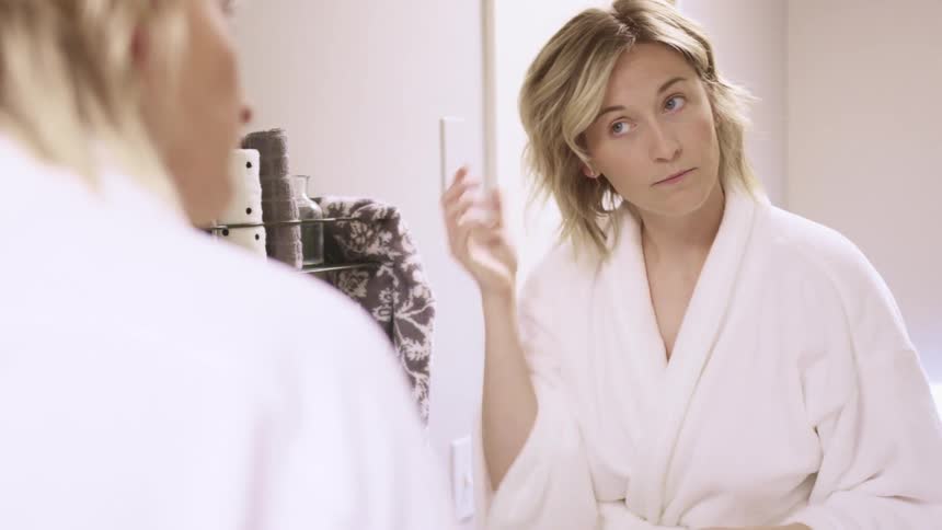 A woman fixing her hair in the mirror