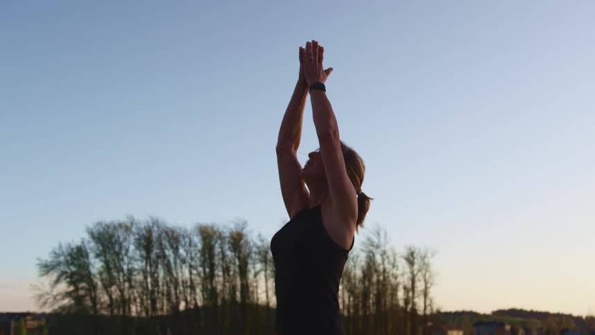 A woman is doing yoga at sunrise