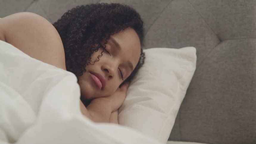 Woman with curly hair falls asleep in bed