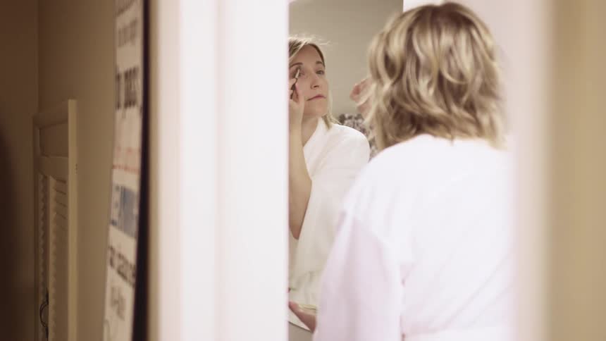 A woman at home puts make up on