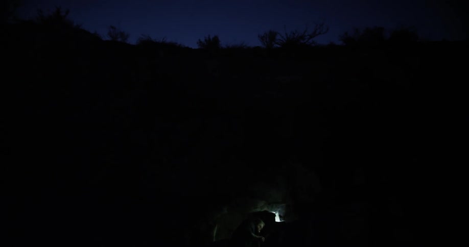 A man shines a flashlight into a hole