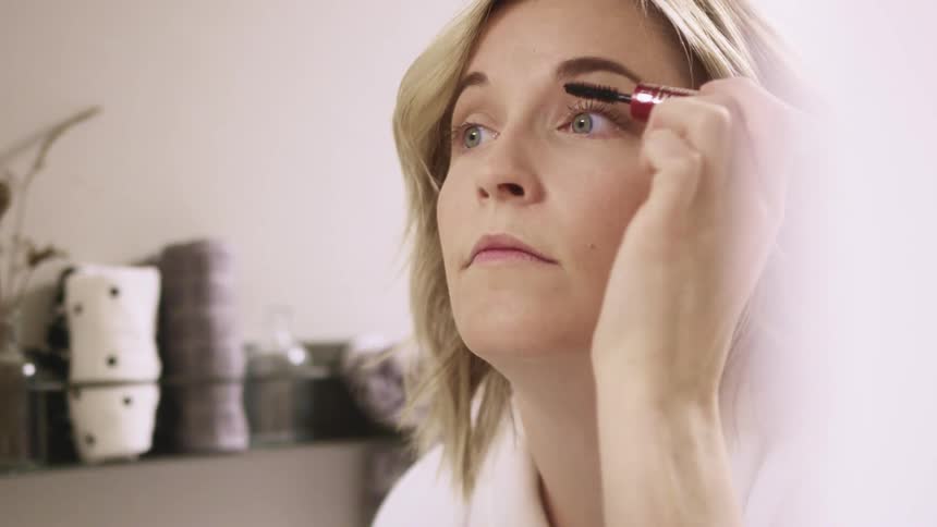 A woman putting on mascara