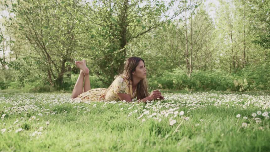 A woman is laying down in the grass