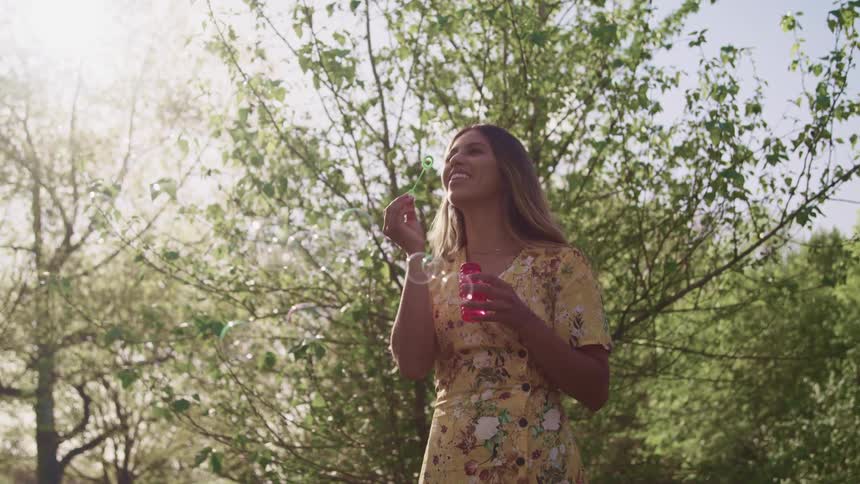 A young woman blowing bubbles outside