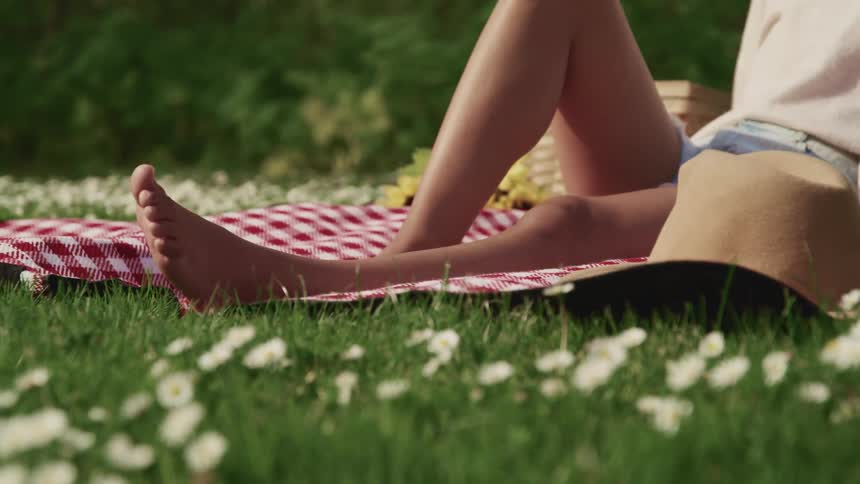 A teenage girl sits on a blanket out in the sun