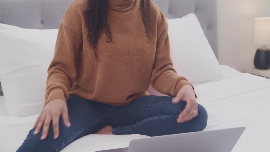 A woman is talking on her laptop in bed