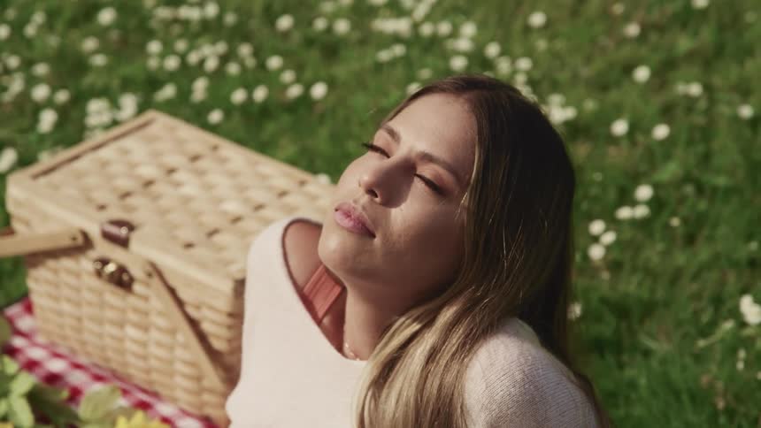 A woman is sitting on the picnic blanket resting
