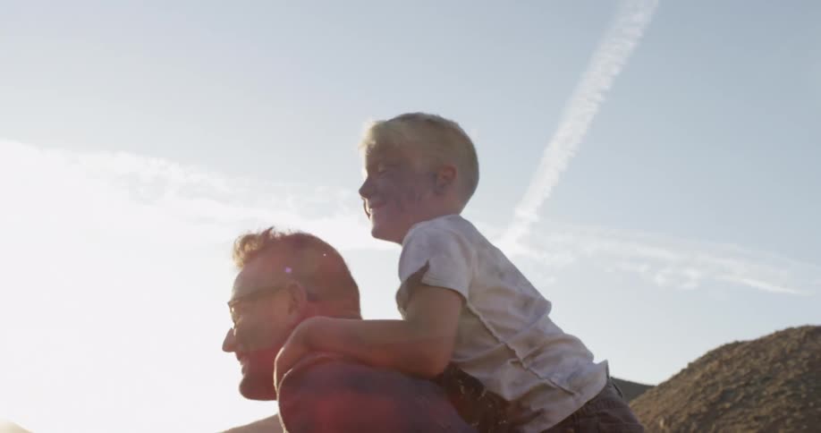 A boy is piggybacking on a man's shoulders