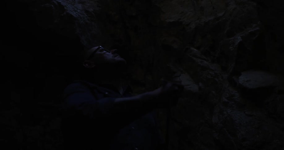Man in cave pulls rope down from above