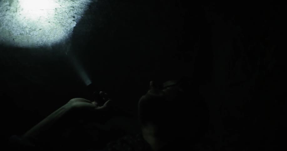 A man shines a flashlight in a dark cave